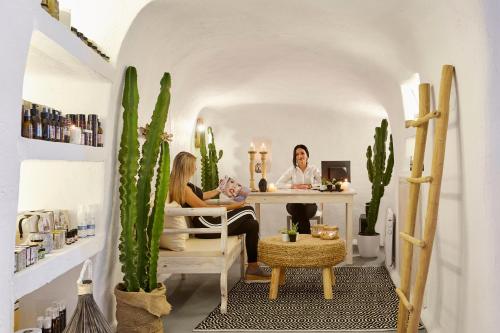 two women sitting at a desk in a room with cactus at Thermes Luxury Villas And Spa in Megalokhori