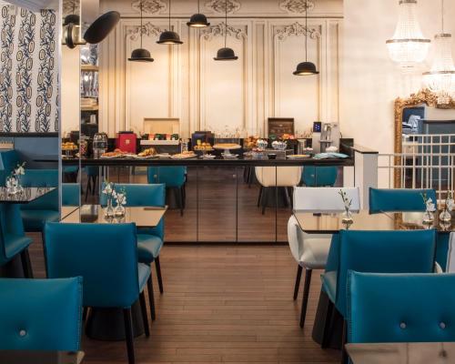 restauracja z niebieskimi krzesłami i barem w obiekcie Hotel Malte - Astotel w Paryżu