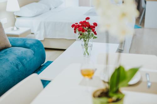 a vase of red flowers on a table in a bedroom at Stephanie Studios in Larnaka