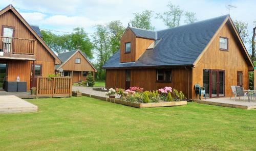 uma grande casa de madeira com um quintal com flores em La Fortuna Lodges em Stirling