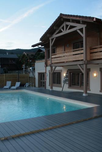 une maison avec une piscine devant une maison dans l'établissement Logis Hotel & Spa Beau-Site, à Saint-Jean-de-Sixt