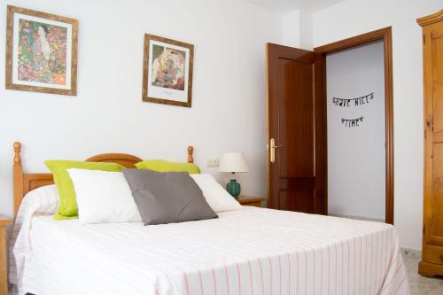 Apartamento Calle Calzada في توروكس: غرفة نوم بسرير ذو شراشف بيضاء ومخدات خضراء
