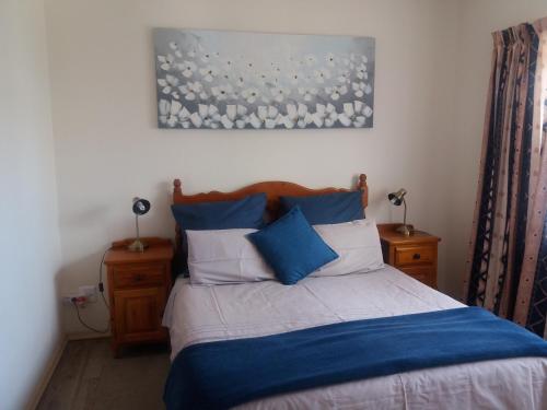 ein Schlafzimmer mit einem Bett mit blauen und weißen Kissen in der Unterkunft Lavendel Cottage in Sedgefield