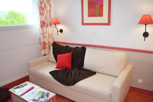 a living room with a white couch with a red pillow at VVF Jura Lac de Vouglans in Maisod