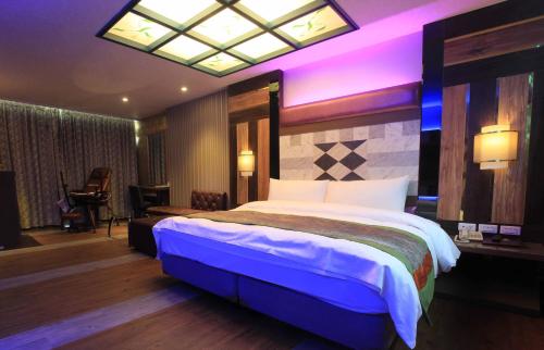 a bedroom with a large bed with a purple lighting at Yue Xin Motel in Miaoli