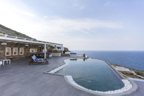 a swimming pool on the side of a building next to the ocean at Naxos Rock Villas in Stelida