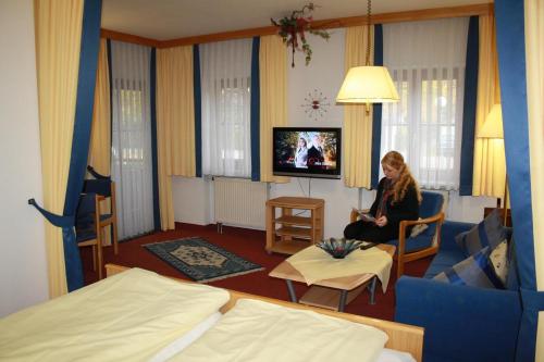 a woman is sitting in a hotel room at Appartement Hotel Finkenhof in Kirchham