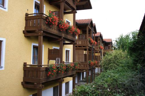 ein Gebäude mit Holzbalkonen und roten Blumen darauf in der Unterkunft Appartement Hotel Finkenhof in Kirchham
