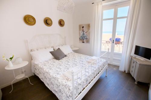 a white bedroom with a bed and a balcony at Azzurro B&B in Cefalù