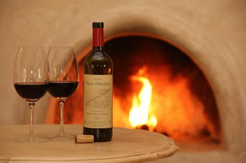 a bottle of wine and two wine glasses in front of a fireplace at Finca Adalgisa in Chacras de Coria