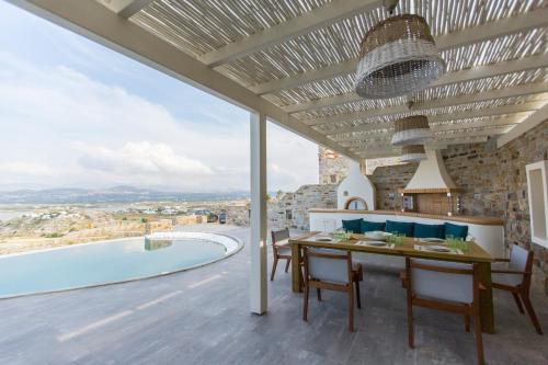 a dining room with a table and a swimming pool at Naxos Rock Villas in Stelida