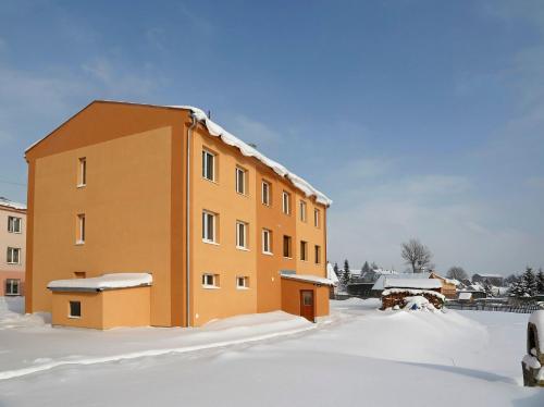 a building with snow on the ground in front of it at Apartmán Abertamy in Abertamy