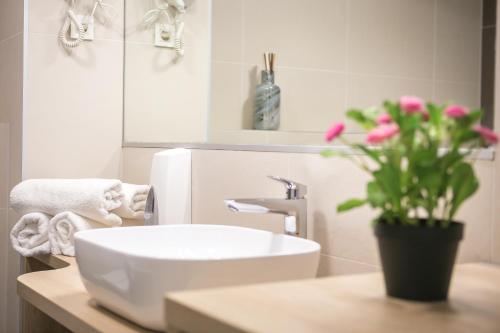 a bathroom with a sink and a vase of pink flowers at Apartment Nova Cesta 62 in Zagreb