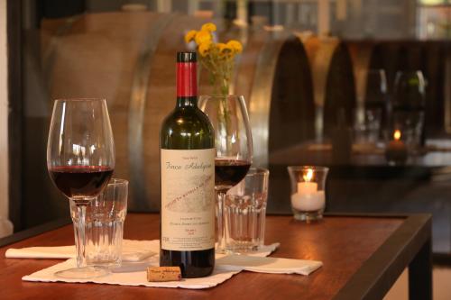 a bottle of wine sitting on a table with two glasses at Finca Adalgisa in Chacras de Coria