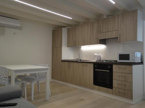 una cucina con armadi in legno e un tavolo con forno a microonde di Appartamento San Tomà a Venezia