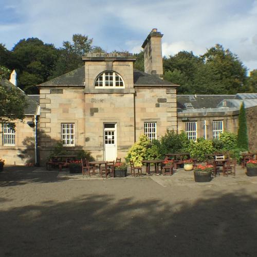 an old stone building with tables and chairs in front of it at Trefoil Apartment - 2 Bedrooms in Glasgow