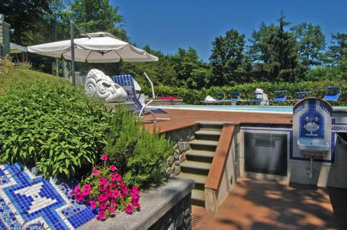 a patio with a pool and an umbrella and flowers at Villa Morelli Gualtierotti in Pontepetri