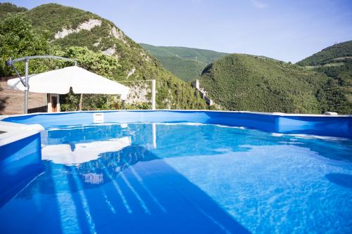 a blue swimming pool with a mountain in the background at Le Rocche Valnerina Residence in Ferentillo