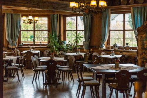 un comedor con mesas, sillas y ventanas en Schmied von Kochel, en Kochel