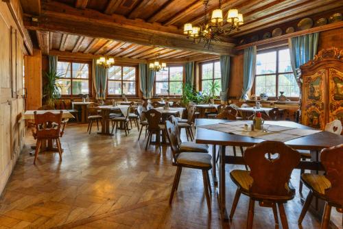 a dining room with tables and chairs and windows at Schmied von Kochel in Kochel