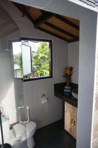 a bathroom with a white toilet and a window at Villa Gede Private Guest House in Selemadeg