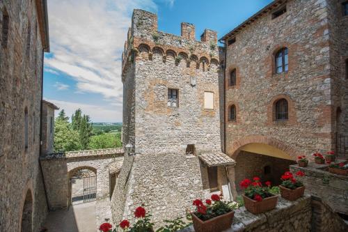 a large stone building with red flowers in a courtyard at Castel Pietraio in Monteriggioni