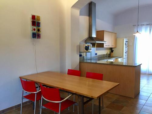uma cozinha com uma mesa de madeira e cadeiras vermelhas em Apartament Can Callis em Castelló d'Empúries