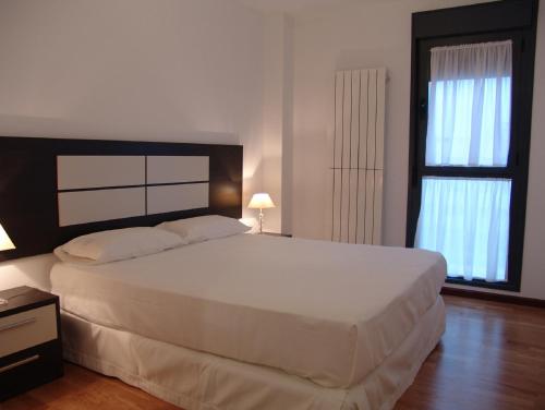 1 Schlafzimmer mit einem großen weißen Bett und 2 Fenstern in der Unterkunft Apartamento Golf Rioja Alta in Cirueña