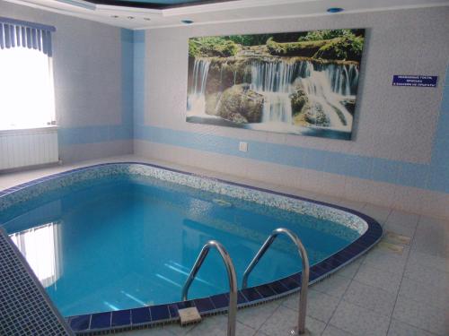 a swimming pool with a waterfall painting on the wall at 1001 Noch Hotel in Tolyatti