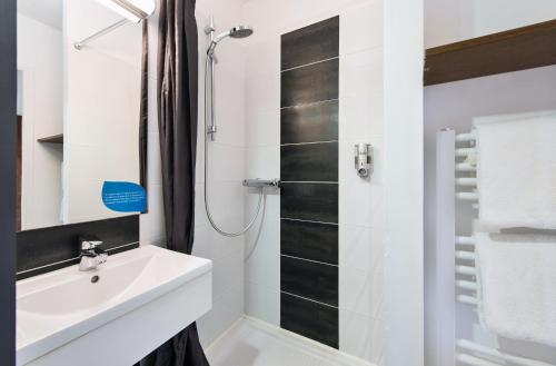 ein weißes Bad mit einem Waschbecken und einer Dusche in der Unterkunft Eco Nuit La Baule Guerande in Guérande