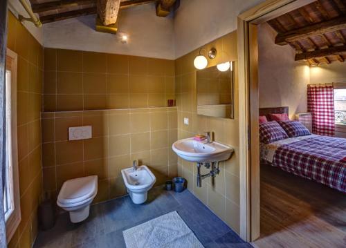a bathroom with a sink and a toilet and a bed at B&B Corte Vignazza in Rovigo