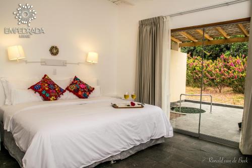 a bedroom with a large white bed and a patio at Empedrada Ranch & Lodge - Hotel Asociado Casa Andina in Caral