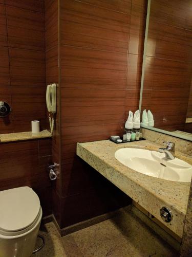 a bathroom with a sink and a toilet and a phone at Blu Petal - A Business Hotel in Bangalore