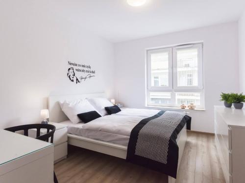 a white bedroom with a bed and a window at VacationClub - Solna Apartment C103 in Kołobrzeg