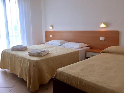 two beds in a hotel room with towels on them at Hotel Madrid in Riccione