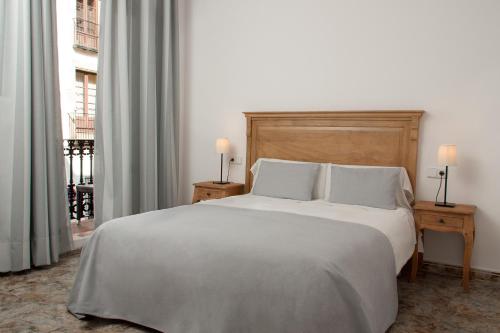 a bedroom with a large white bed with two lamps at Hostal Portofino in Arenys de Mar