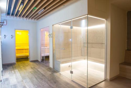 a glass shower in a bathroom with a yellow door at SeaPark Hotel Wellness & Spa in Kołobrzeg