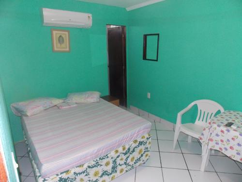 a bedroom with a bed and a table and a chair at Pousada Bom Jesus in Tamandaré