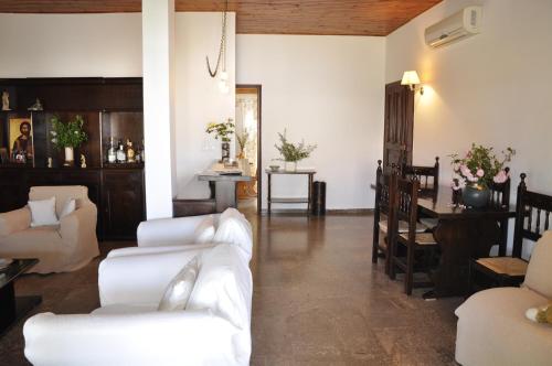 a living room with white couches and a dining room at Ava Apartments in Agios Gordios
