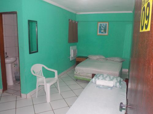 a bedroom with a bed and a chair and a sink at Pousada Bom Jesus in Tamandaré