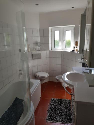 ein Badezimmer mit einer Badewanne, einem WC und einem Waschbecken in der Unterkunft Ferienwohnung Cuxhaven in Cuxhaven