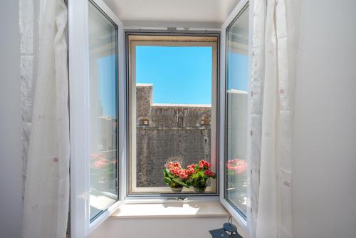 a window with a vase of flowers on a window sill at Fora Apartments in Dubrovnik