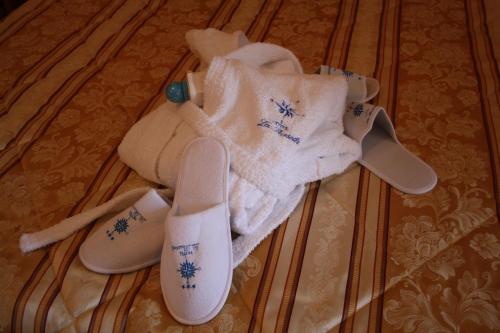 a pile of towels and slippers on a bed at Hotel La Bussola in Andalo