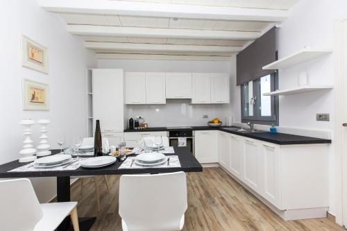 a kitchen with white cabinets and a table with white chairs at Naxos Rock Villas in Stelida