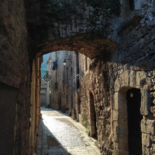 an alley with an archway in a stone building at Chez les artistes in Servian