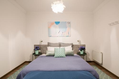 una camera da letto con un grande letto con lenzuola e cuscini viola di St.Roland Livu Square a Riga