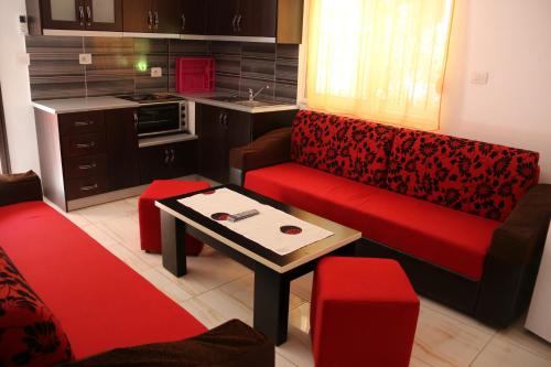 a living room with a red couch and a table at Olive Tree Apartment in Sarandë