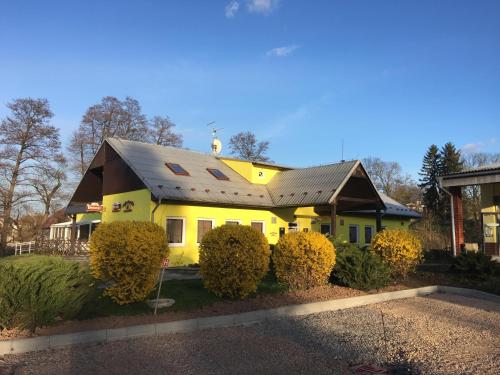 a yellow house with a metal roof and some bushes at Penzion Krásný Dvůr in Krásný Dvŭr