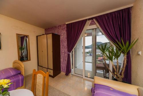 a living room with purple curtains and a large window at Apartmani Marija in Sutomore
