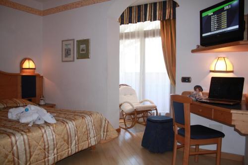 a child sitting in a hotel room with a laptop at Hotel La Bussola in Andalo